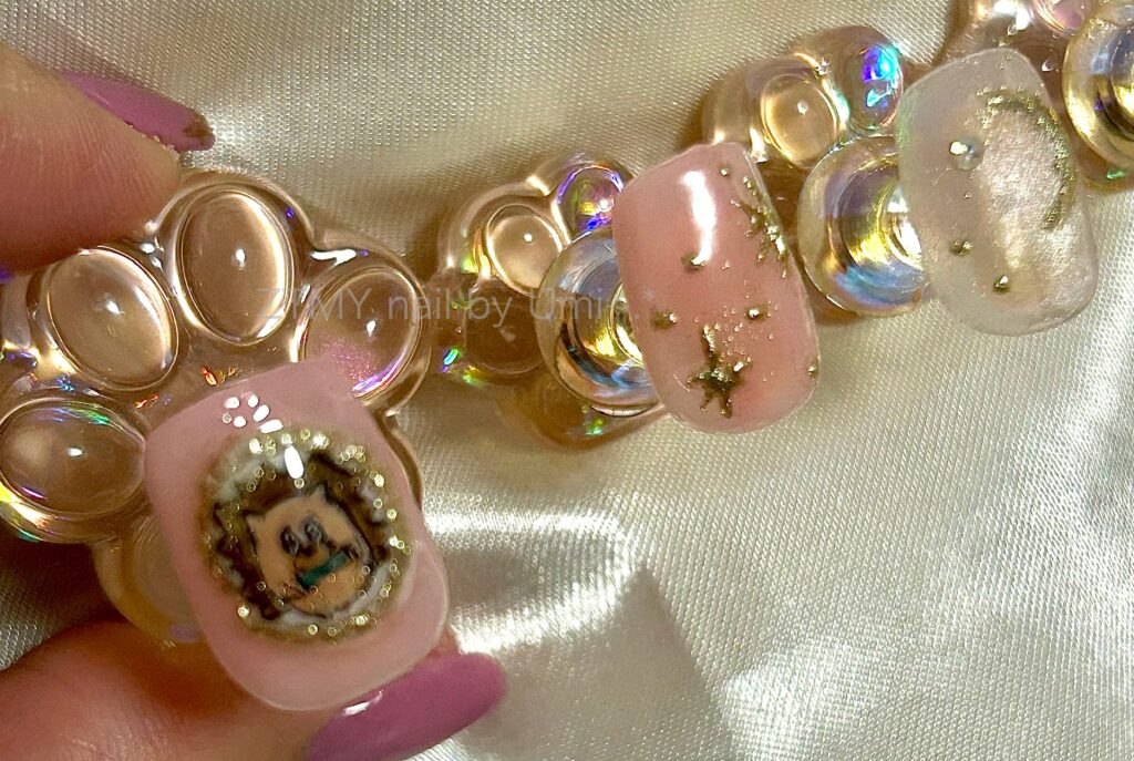 alt="うにぐりくんのブローチ風ネイルパーツとミラーパウダーで模様を描いたピンクネイル"